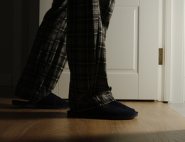 A pair of pajama- and slipper-clad legs enter a bathroom at night.