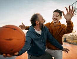 A father and son play basketball.