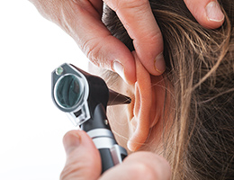 A doctor is using a scope to look inside a woman's ear.