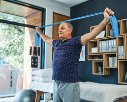 An older man using an exercise band. 