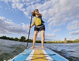 A middle-aged woman on a paddleboard in a lake.