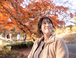 A woman smiles up at an autumn sky